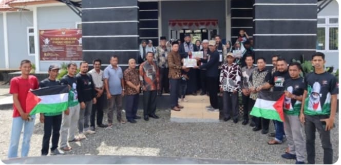 Sekelompok orang berdiri di depan gedung berbendera, menggalang dana donasi sebesar Rp.100 Juta untuk Palestina untuk mendukung Masyarakat Suak Puntong.