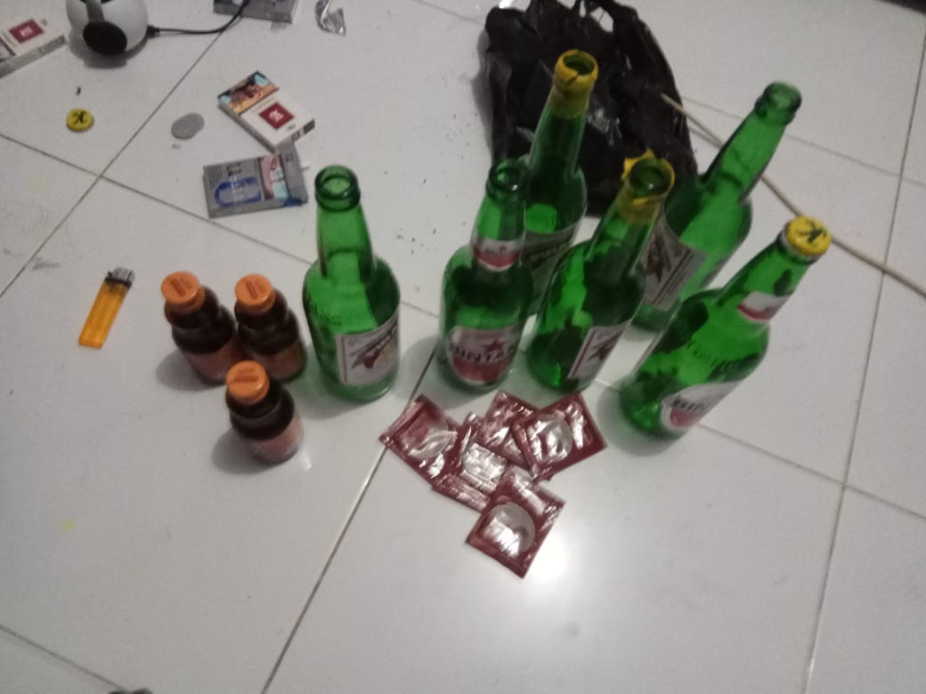 Sekelompok botol bir hijau di lantai keramik, disusun secara artistik.