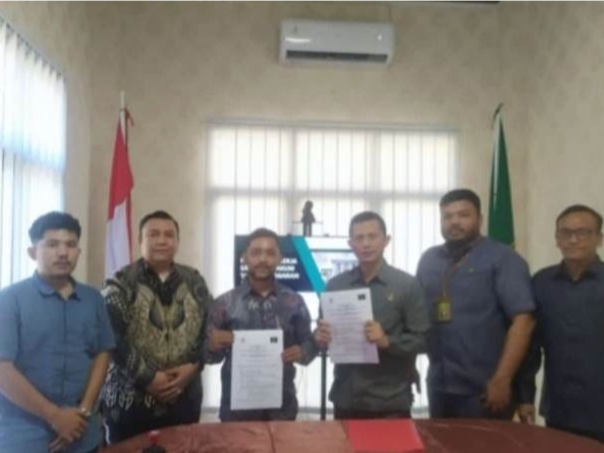 Sekelompok orang berdiri mengelilingi meja sambil memegang kertas YLBH.